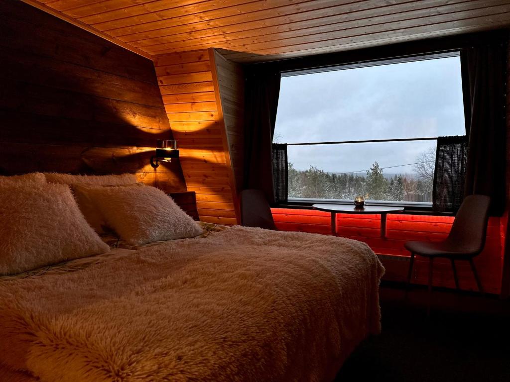 a bedroom with a bed and a window and a table at Jättiläisenmaa in Paltamo