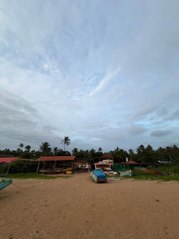 a group of buildings on a dirt field with a sky at Dolphin beach in Varkala