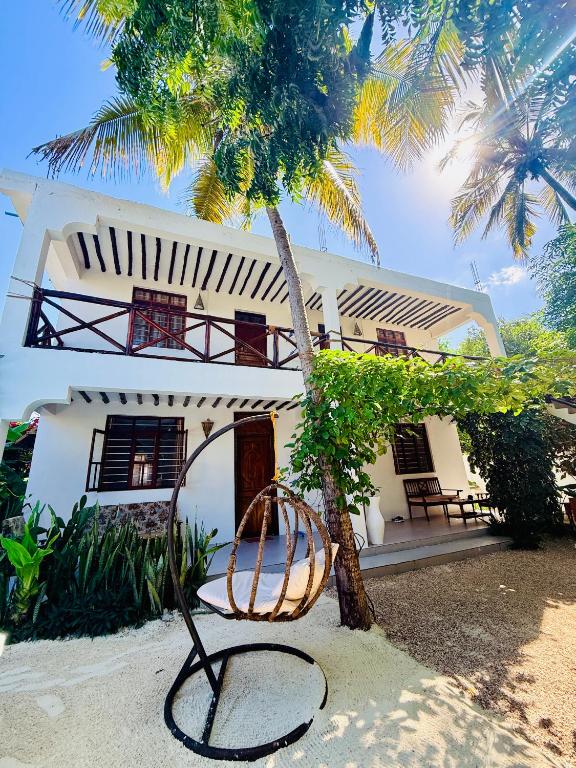 a chair in front of a house with a palm tree at Peace and Love Villa in Jambiani