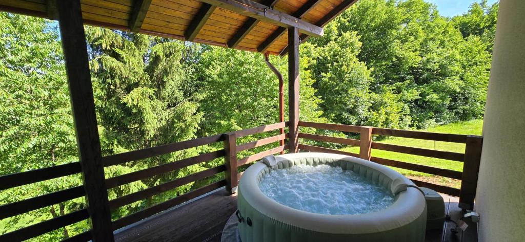 a hot tub sitting on a deck with a fence at B&B Green Serenity Plitvice Lakes in Plitvička Jezera