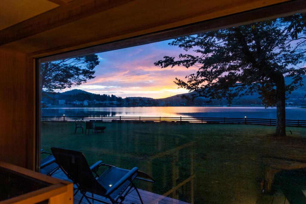 a view of a lake from a window with chairs at marinoe organic resort - Health and Stay - A Private Lakeside Villa at Lake Yamanaka, Blessed by the Spirit of Mount Fuji in Yamanakako