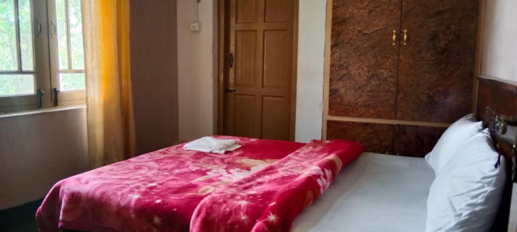 a bed with a red comforter in a room at Mullberry Lodge Gulmit in Chamangul
