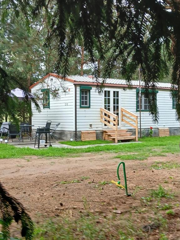 a white house with a bench and a picnic table at Sosnowa Polana in Lipinki