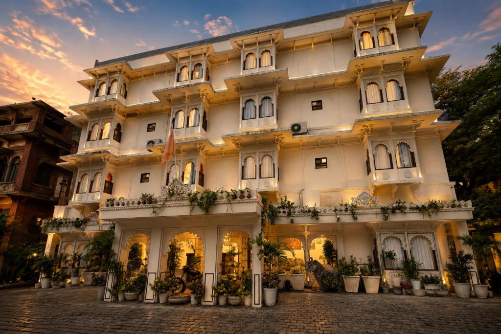 a large white building with potted plants in front of it at Kaner Bagh A Heritage Boutique Hotel in Udaipur