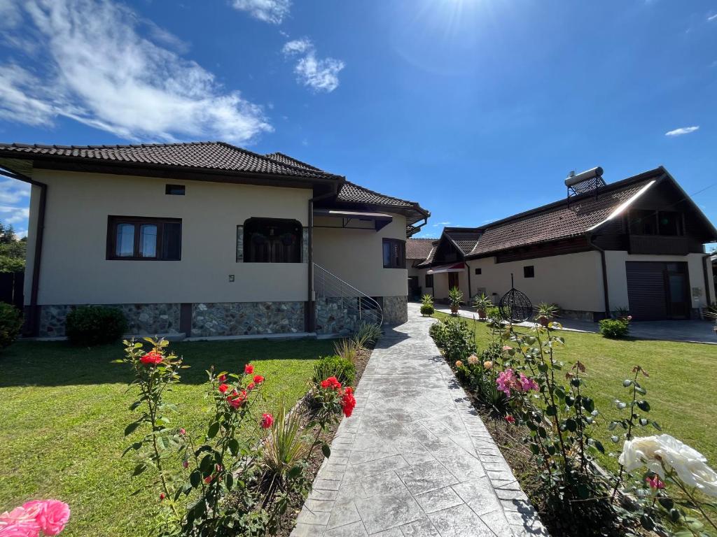 a house with a garden with flowers in the yard at Cazare Sandy in Novaci-Străini