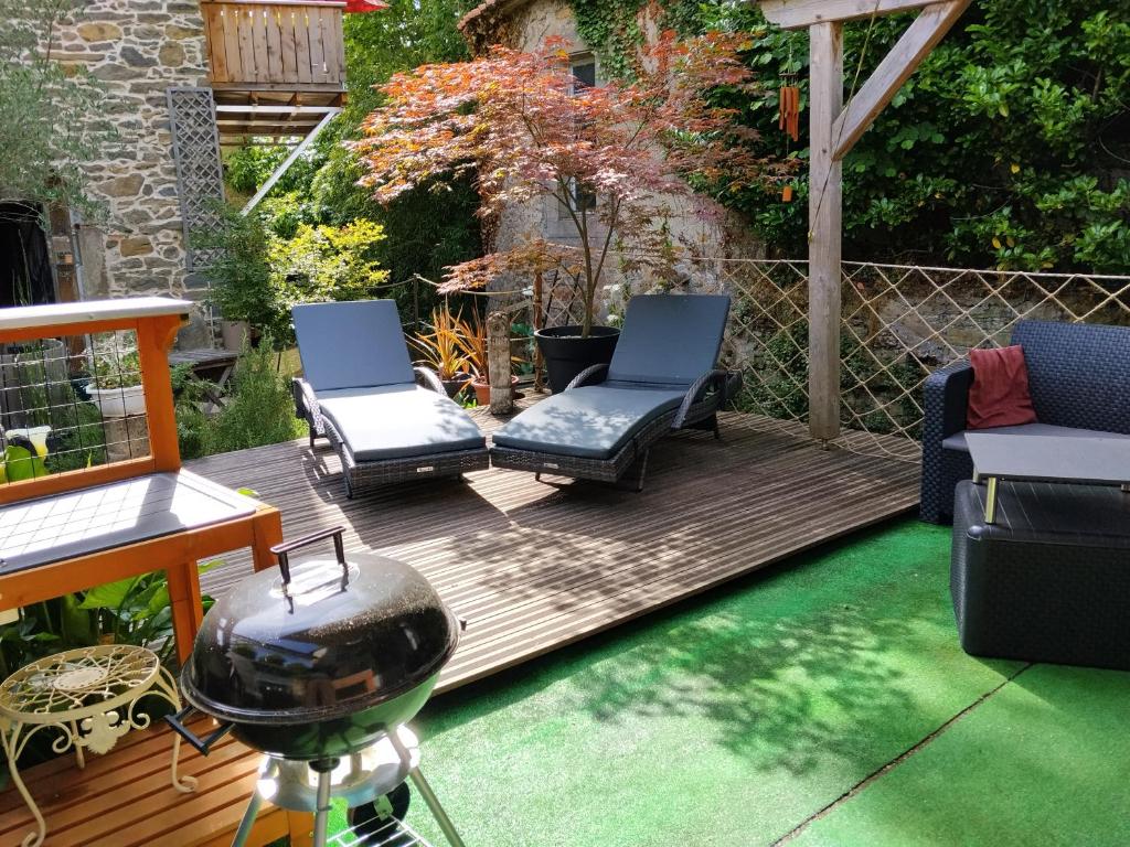 a patio with two chairs and a grill on a deck at Relaxing Gite aux fil de l'eau in Sainte-Colombe-sur-lʼHers