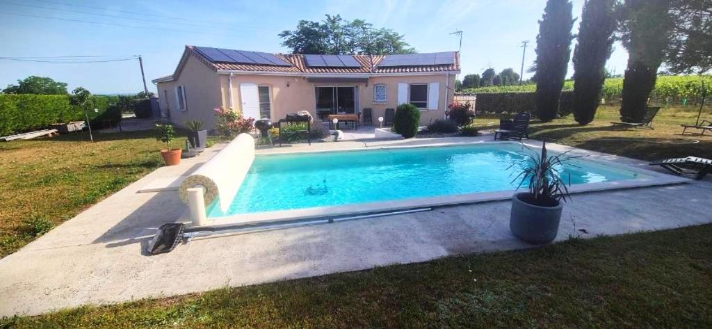a swimming pool in front of a house at La maison dans les vignes in Châteauneuf-sur-Charente