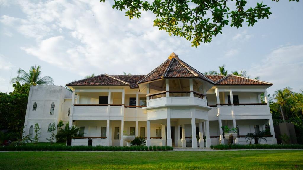 a large white house with a tiled roof at Amandalay Hotel & Villas in Karimunjawa