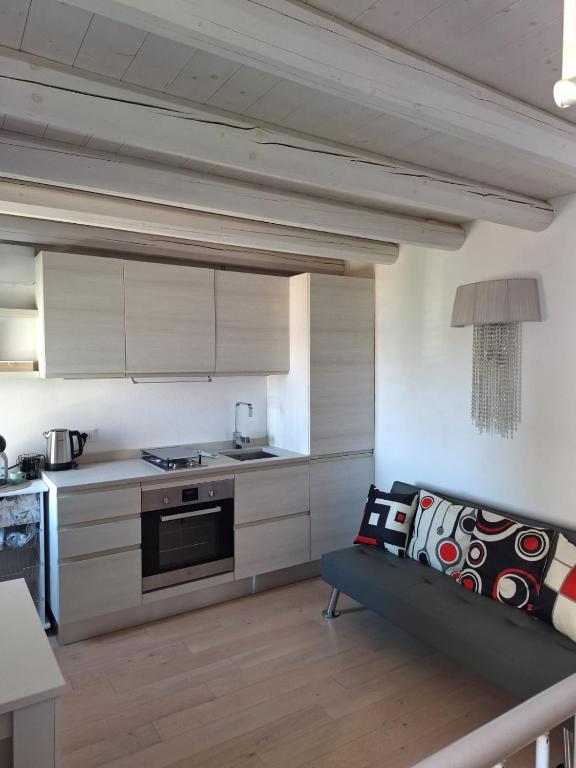 a kitchen with white cabinets and a couch in a room at Lagunahome Beatrice in Chioggia