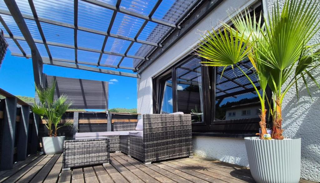 a patio with two chairs and palm trees on a deck at Klein aber fein in Hinterweidenthal