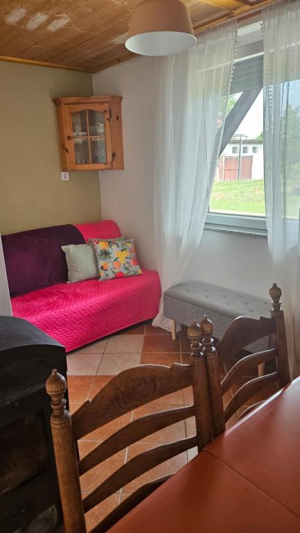 a living room with a red couch and a window at Zinnia Vendégház in Nagyrada