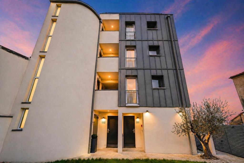 a tall white building with a sunset in the background at JIJI Suites Sénart in Combs-la-Ville