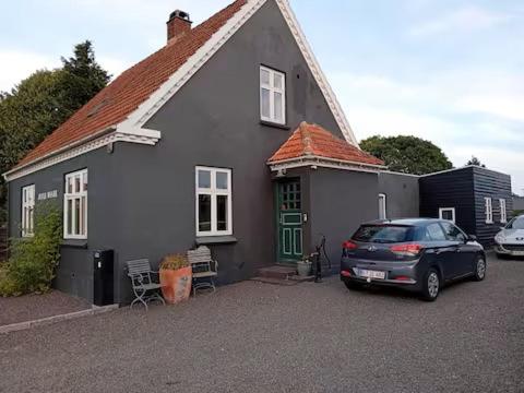 a gray house with a car parked in front of it at Bed and Boat in Præstø
