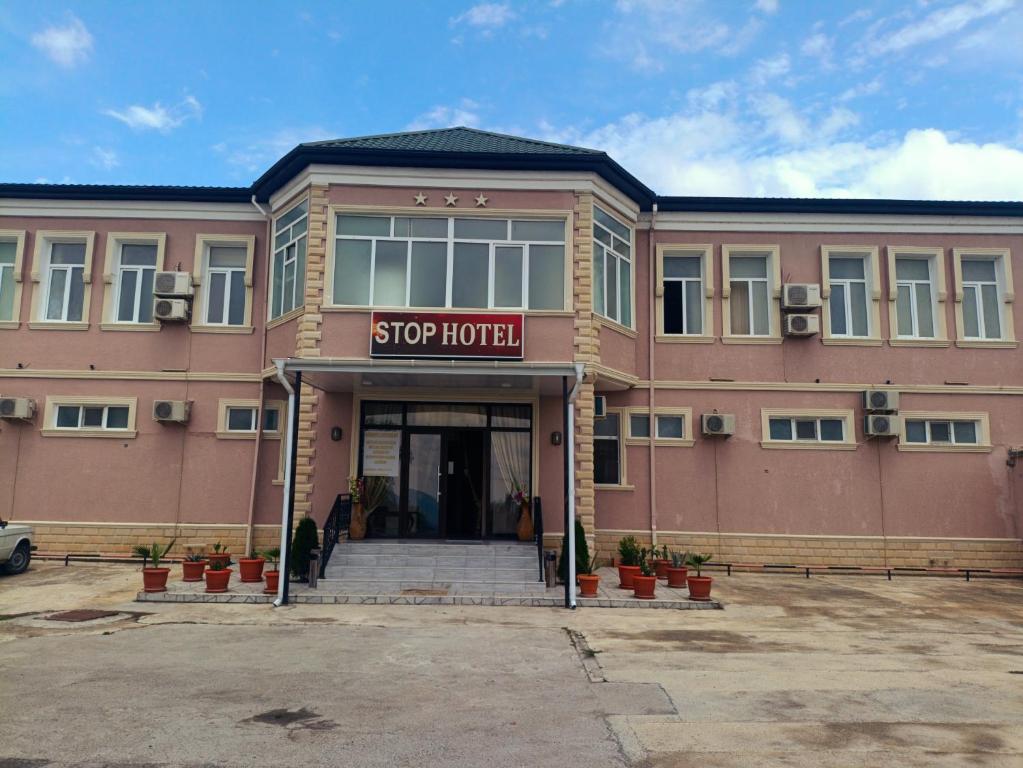a large pink building with a sign that reads stop hotel at STOP otel in Sheki