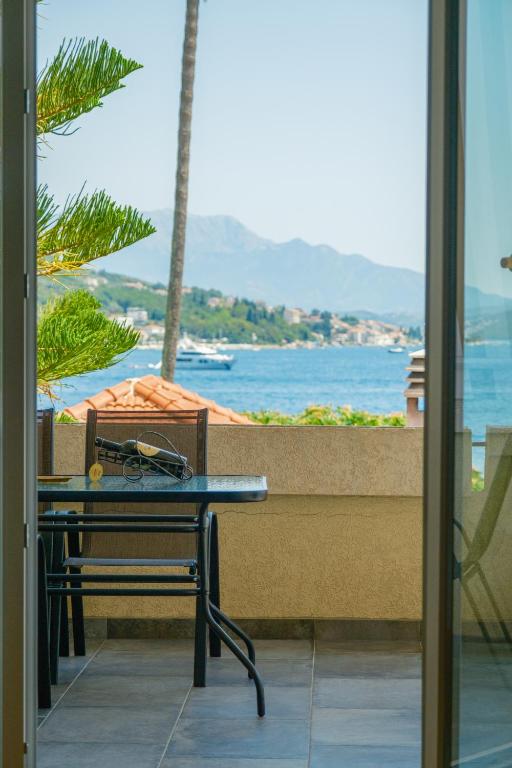 a table and a chair with a view of the ocean at Apartments Danilo in Herceg-Novi