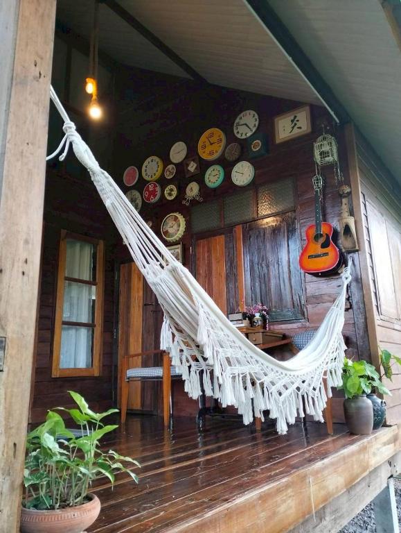 a hammock on a porch of a house with a guitar at Tamarind nest in Sai Yok