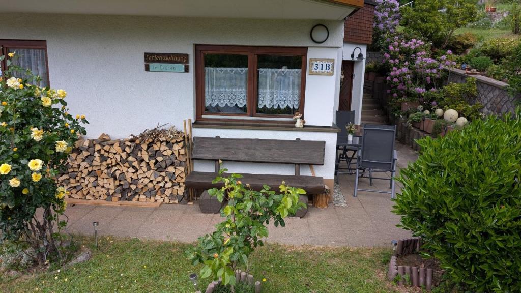 a house with a bench and a pile of fire wood at FeWo im Grünen in Häusern