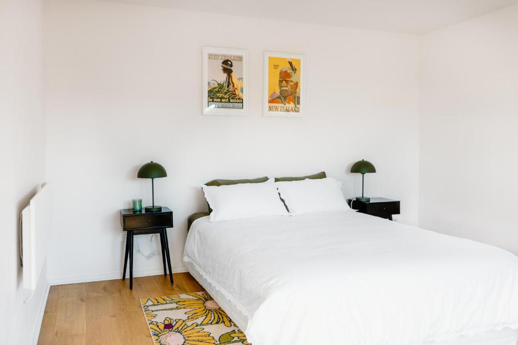 a white bedroom with a white bed and two lamps at The Albert Studio in Albert Town