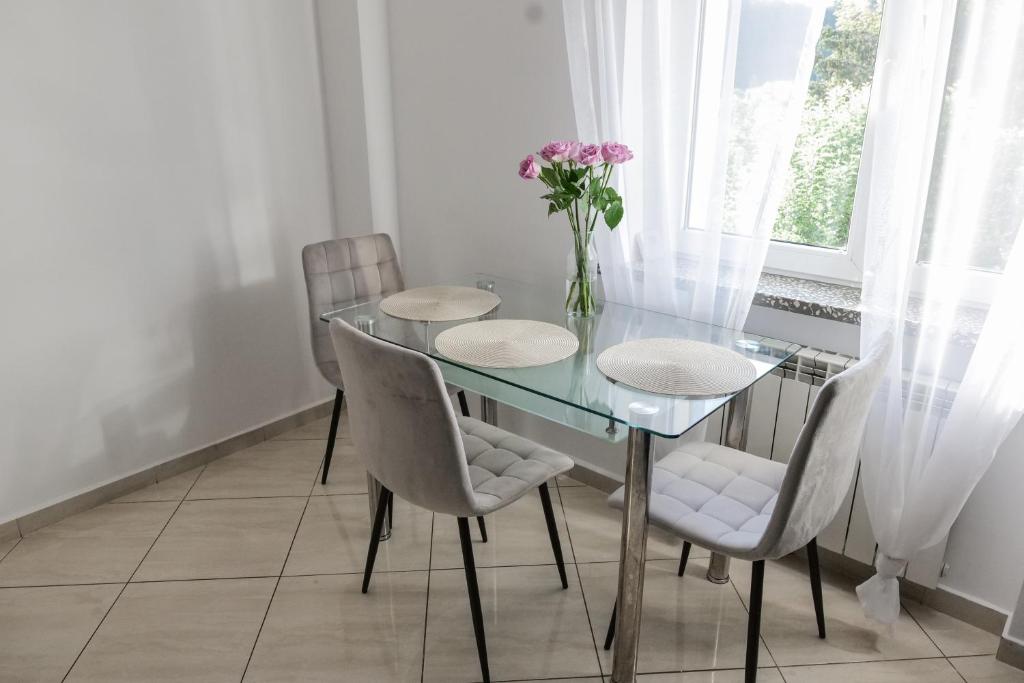 a dining room table with chairs and a vase of flowers at Apartament Ogrodowa in Muszyna