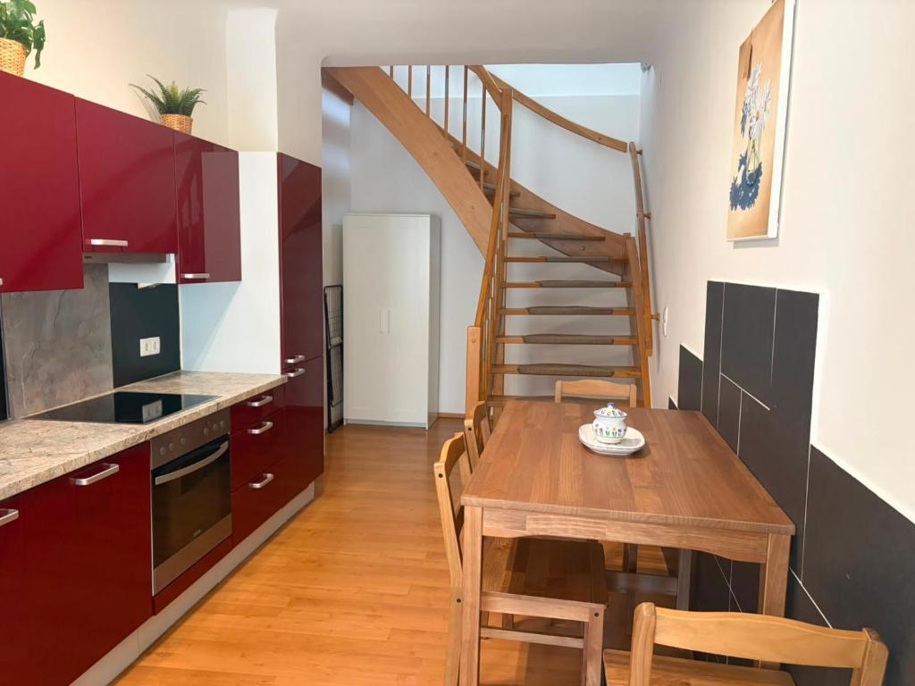 a kitchen and dining room with a wooden table and a staircase at Ferienwohnung Zum alten Postamt in Mörbisch am See
