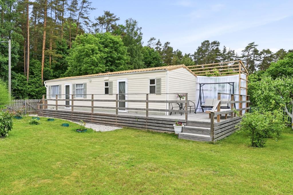 a mobile home with a deck in a yard at Vagunmaja in Haapsalu