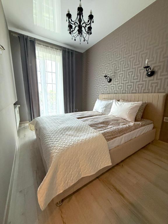 a bedroom with a large bed and a chandelier at Lielais prospekts 54 in Ventspils