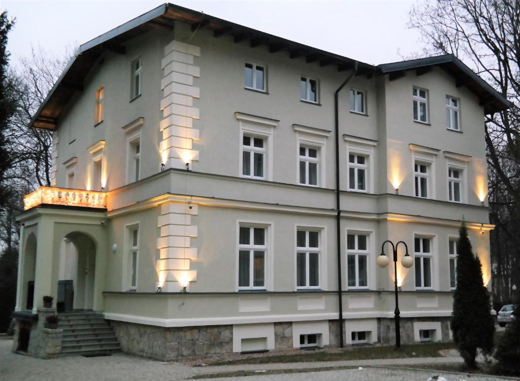 a large white house with lights on it at Willa Mała Pieniawa in Polanica-Zdrój