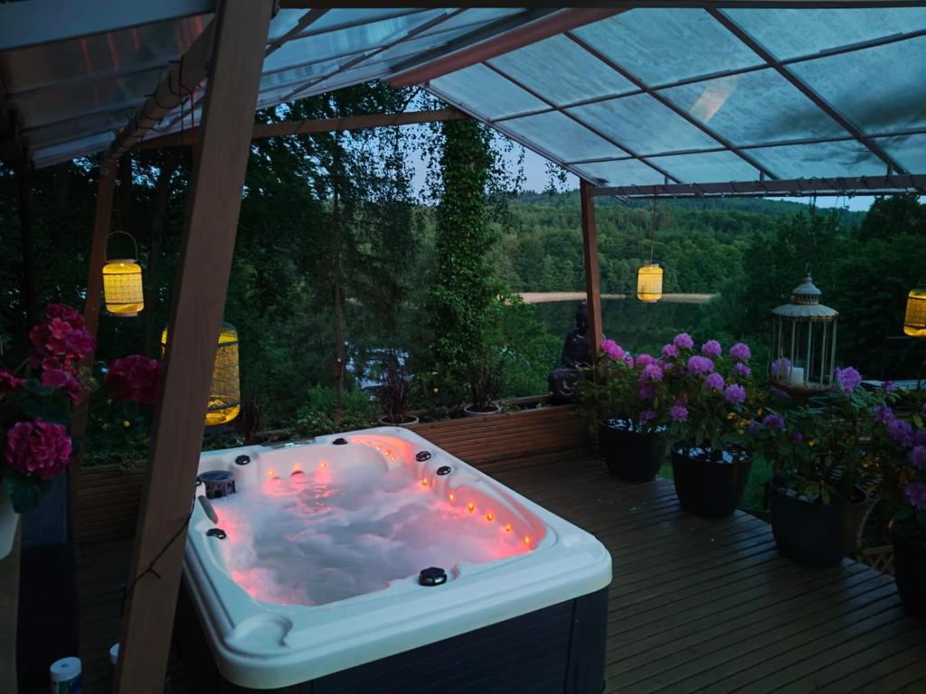 a jacuzzi tub on a deck with flowers at Mała Garda in Brodnica Dolna