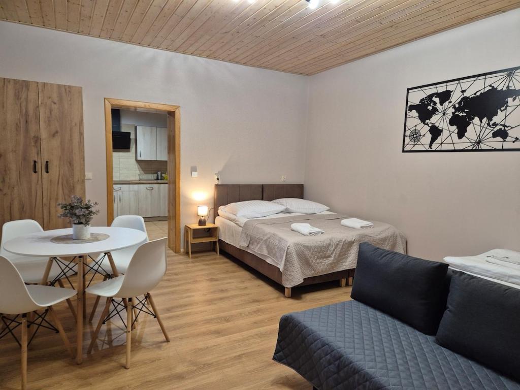 a bedroom with a bed and a table and a couch at Apartment Pod Modrzewiem in Powidz