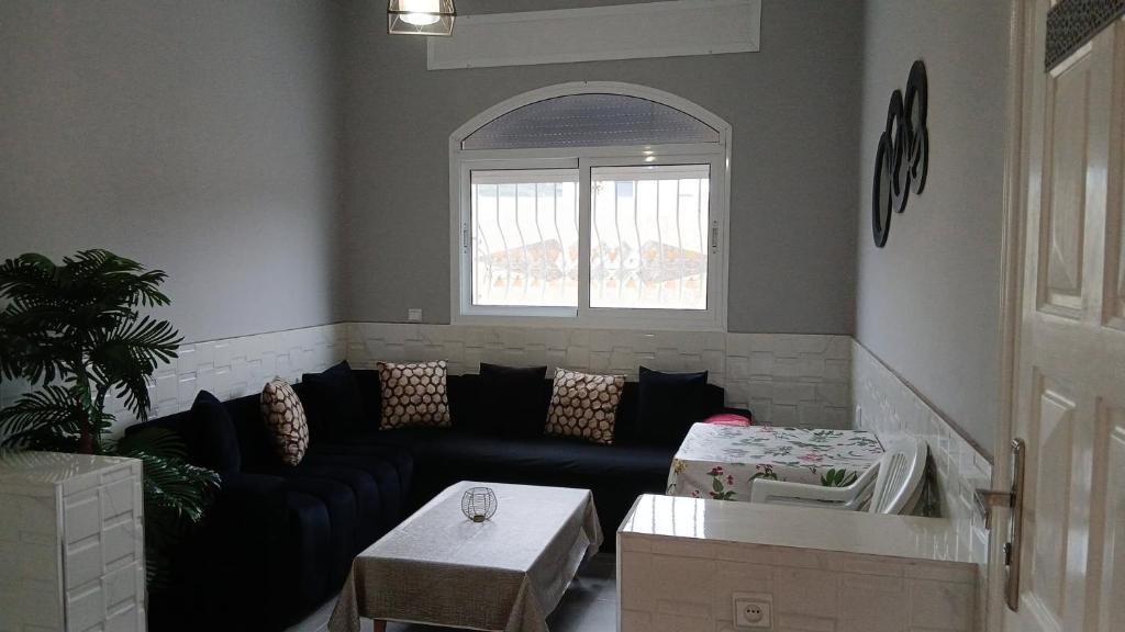 a living room with a black couch and a window at Acacia Nest in Tangier