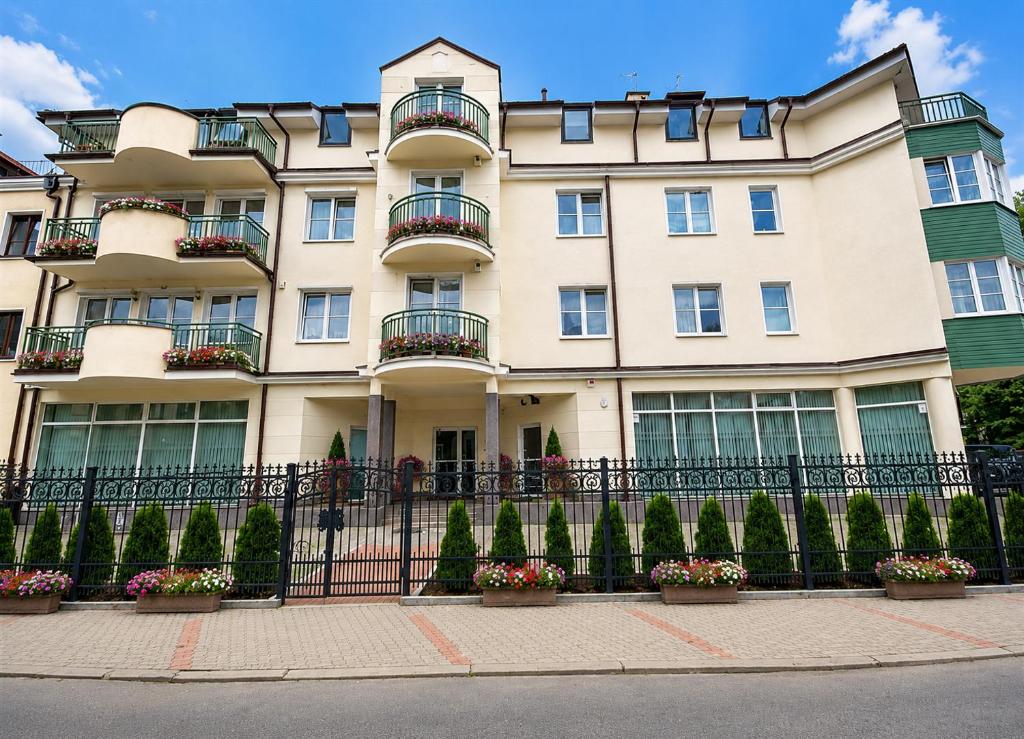 a large building with flowerpots in front of a fence at Extra Apartamenty - Apartament przy plaży in Sopot
