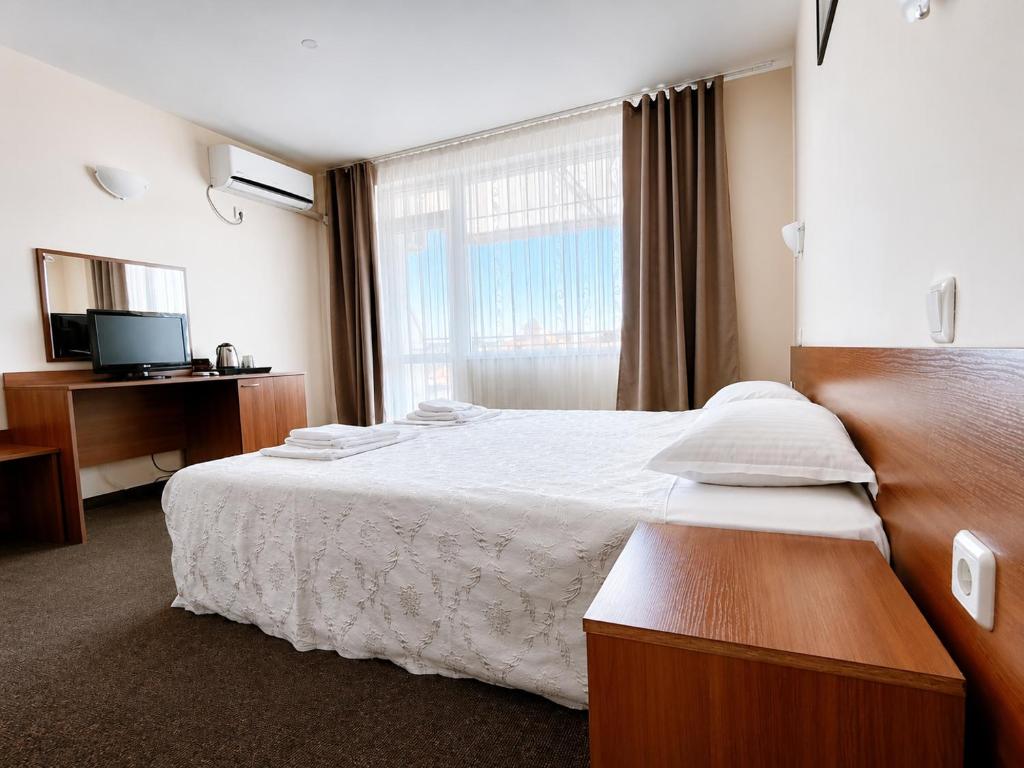 a hotel room with a bed and a window at Sandor Hotel in Nesebar
