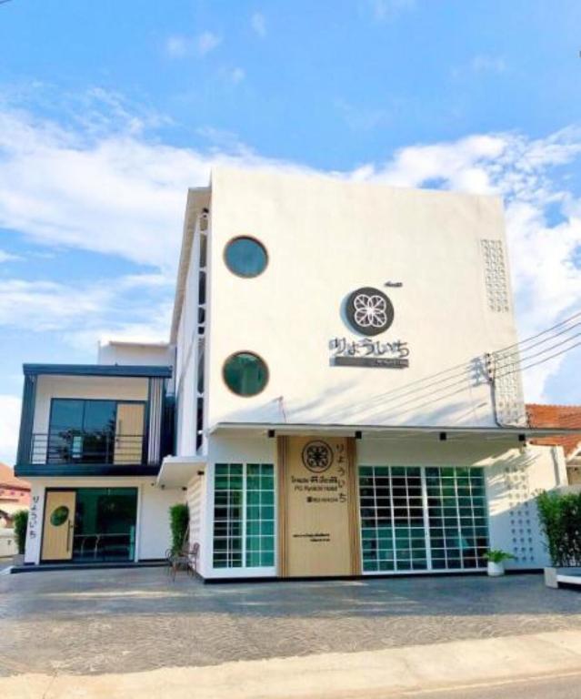 a white building with green windows on the side of it at PG Ryoichi Hotel in Chiang Rai