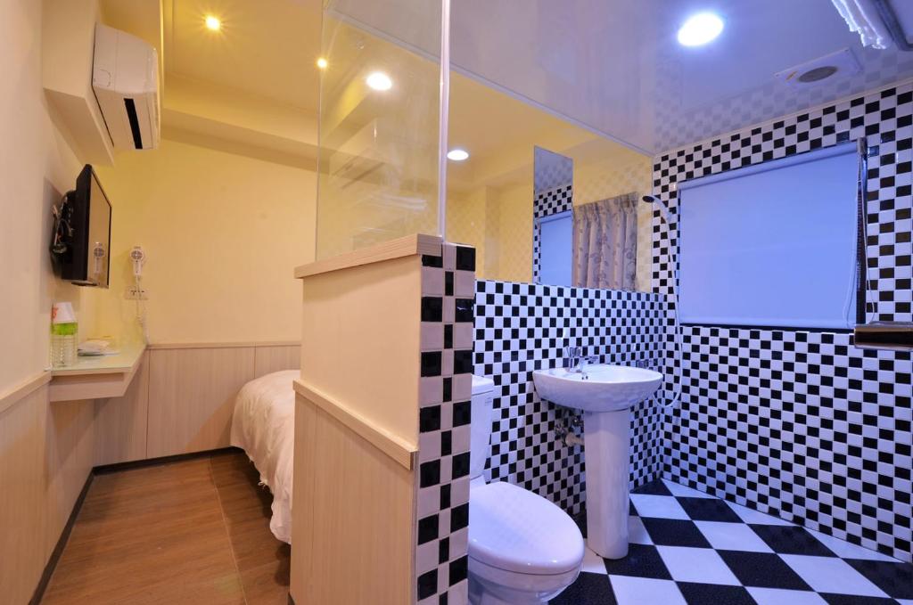 a bathroom with a checkered floor and a toilet and a sink at Galaxy Mini Inn in Taipei