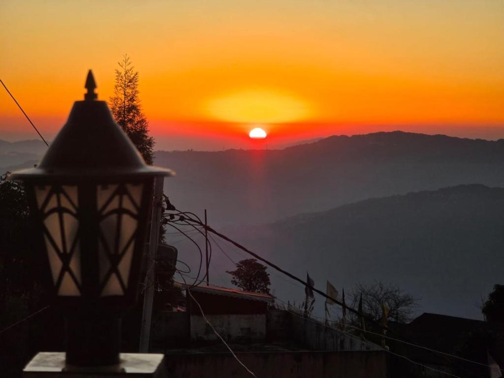 a sunset in the mountains with a street light at The Dusk Stay in Sonāda