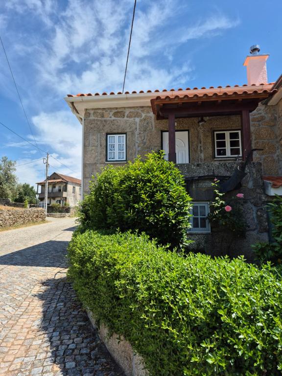 a stone house with a red roof on a brick road at Casa das Pédrinhas Pousade Guarda in Guarda