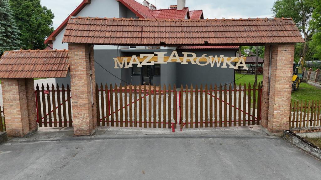 a garage with a gate in front of a building at Maziarówka in Basznia Dolna