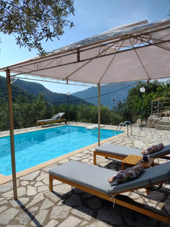 a pool with two lounge chairs and an umbrella at IthakiHouse II in Vathi