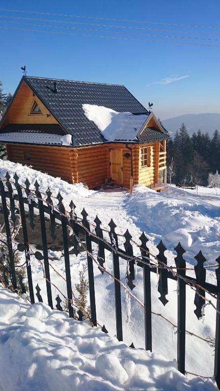 a log cabin in the snow with a fence at Domek drewniany simonka zawoja in Zawoja