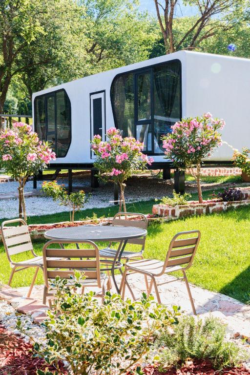 a rv parked in a yard with a table and chairs at EloA Glamping in Petrovac na Moru