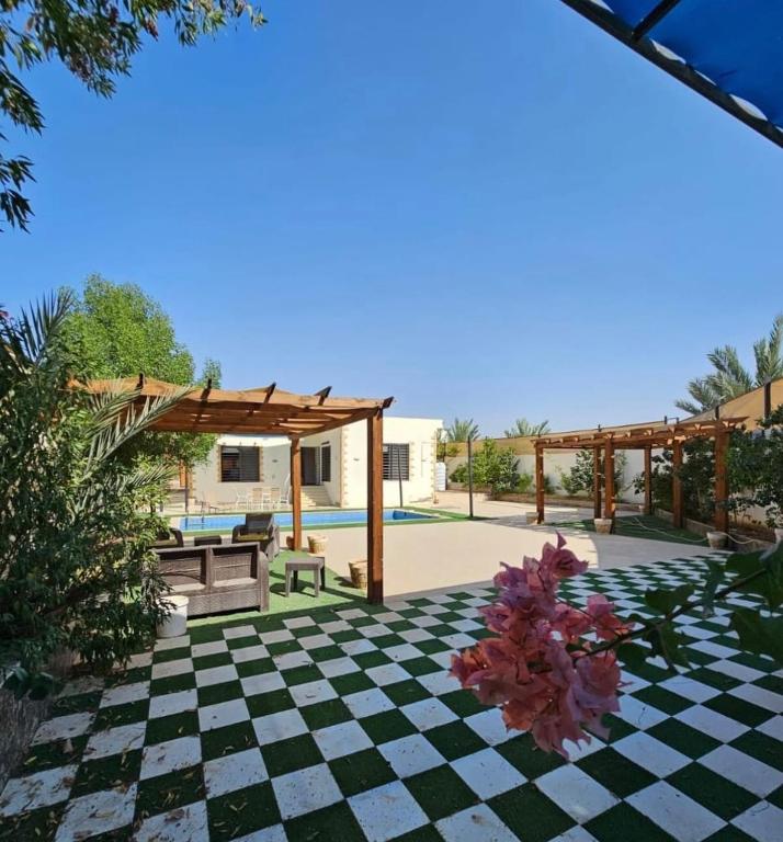 a patio with a checkered floor and a pergola at Shamsa Chalet in Al Mazār