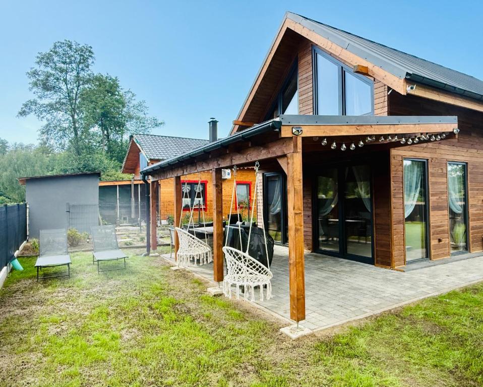 ein Holzhaus mit Terrasse und Stühlen in der Unterkunft Venice barn Przełazy in Przełazy