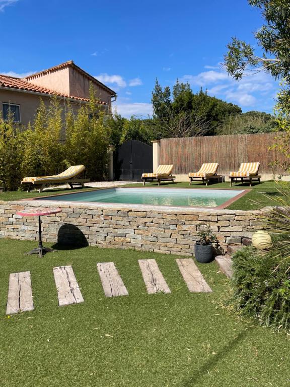 a backyard with a swimming pool with benches and a stone wall at Chambre Villa piscine in Saint-Tropez
