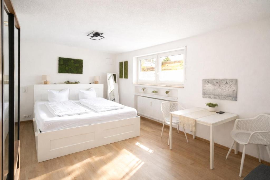 a white bedroom with a bed and a table at *moderne Wohnung ANTON in VS mit Küche+Bad in Villingen-Schwenningen