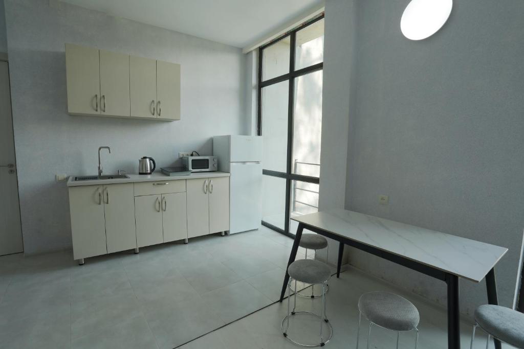 a kitchen with white cabinets and a table and chairs at Shekvetili Sunset Apartments in Shekhvetili