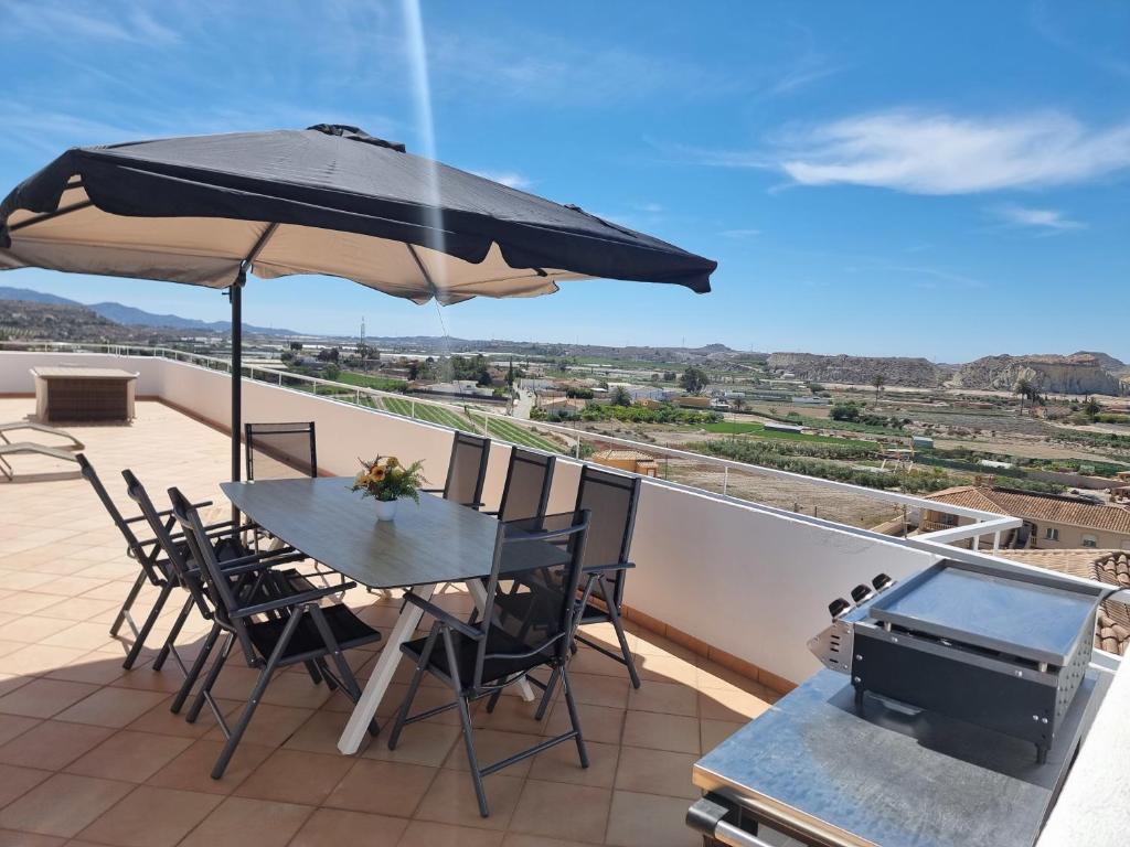 a table and chairs on a balcony with an umbrella at villa piscina y vistas espectaculares a la montana , gran terraza y aire acondicionado in Cuevas del Almanzora