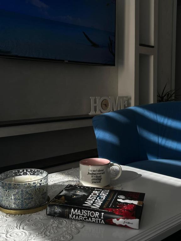 a table with a book and a cup of coffee on it at Apartman Nastić in Lazarevac