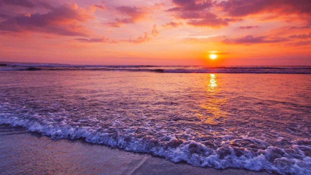 a sunset on the beach with the waves at Cosy Studio in Port Douglas