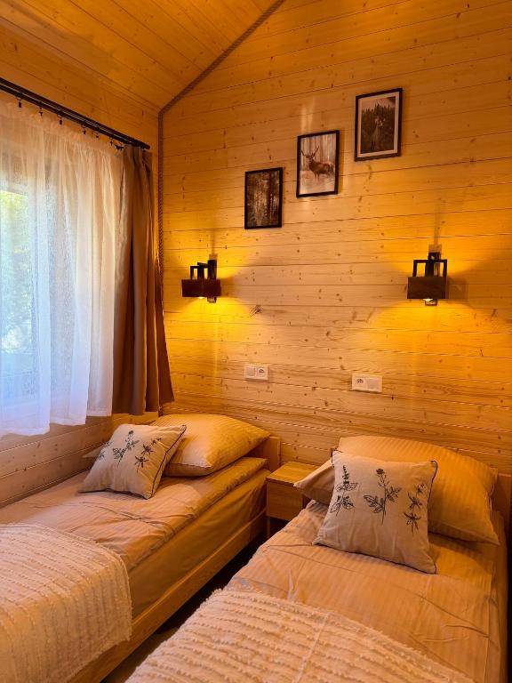 a bedroom with two beds in a log cabin at Las Się Żyje in Lutowiska