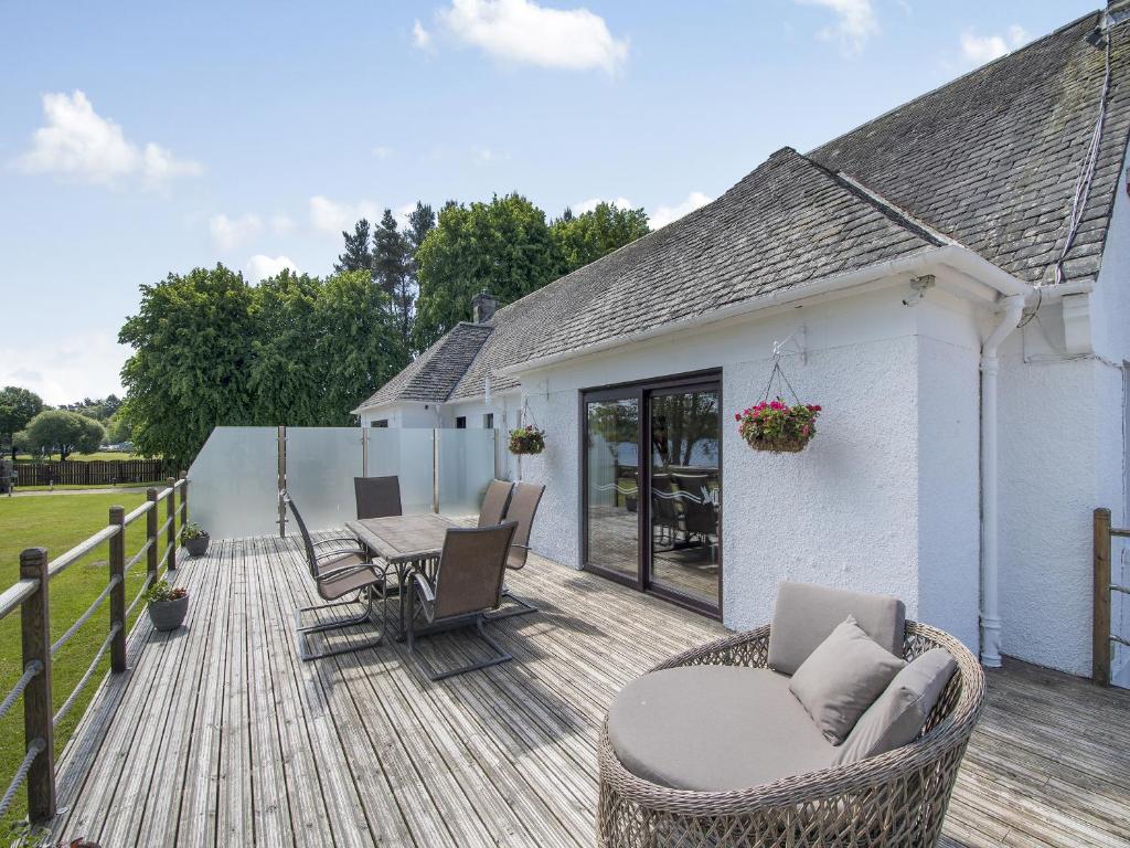 a wooden deck with a table and chairs on it at Duck Bay Cottage 2 - Uk43935 in Balloch